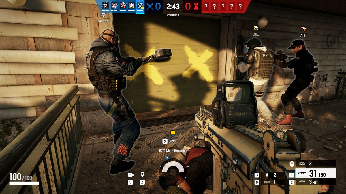 Capture officielle de Rainbow Six Siege : un attaquant frappe à la masse une paroi marquée de deux croix jaunes pour l'ouvrir, pendant qu'un porteur de bouclier et une coéquipière attendent contre le mur