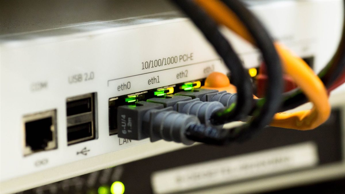 Photo en gros plan de câbles Ethernet branchés sur un routeur aux voyants allumés, illustrant une connexion filaire stable pour le jeu en ligne