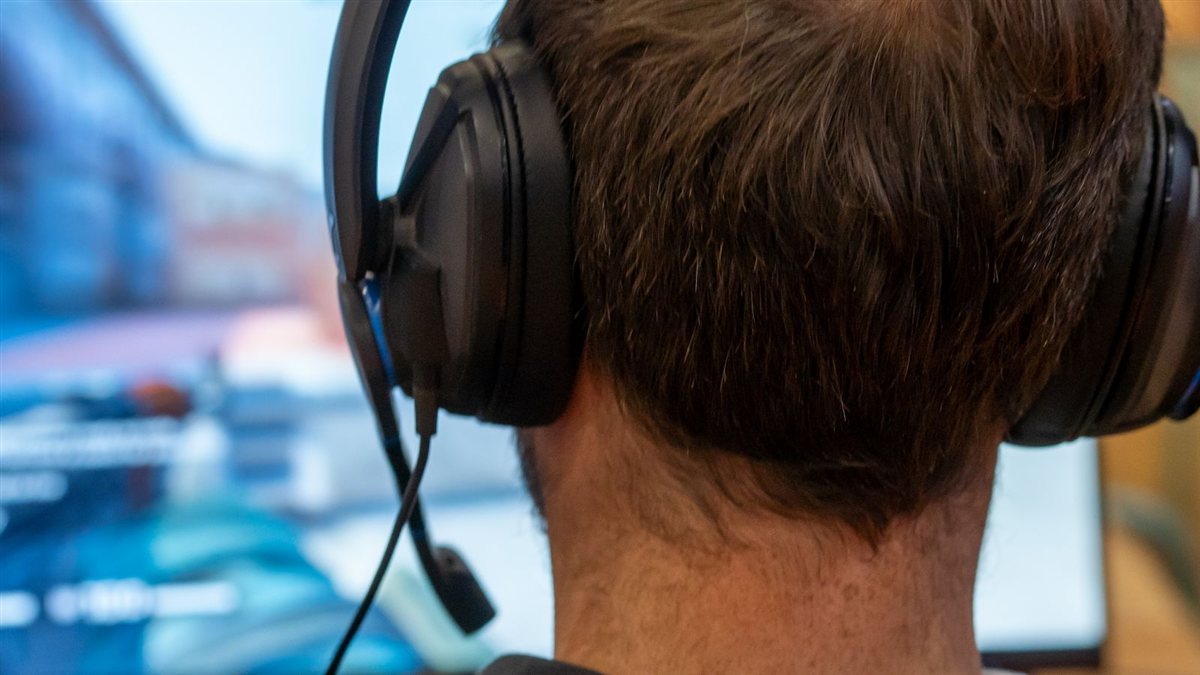 Photo d'illustration : un joueur vu de dos, casque sur les oreilles, devant son écran de jeu.