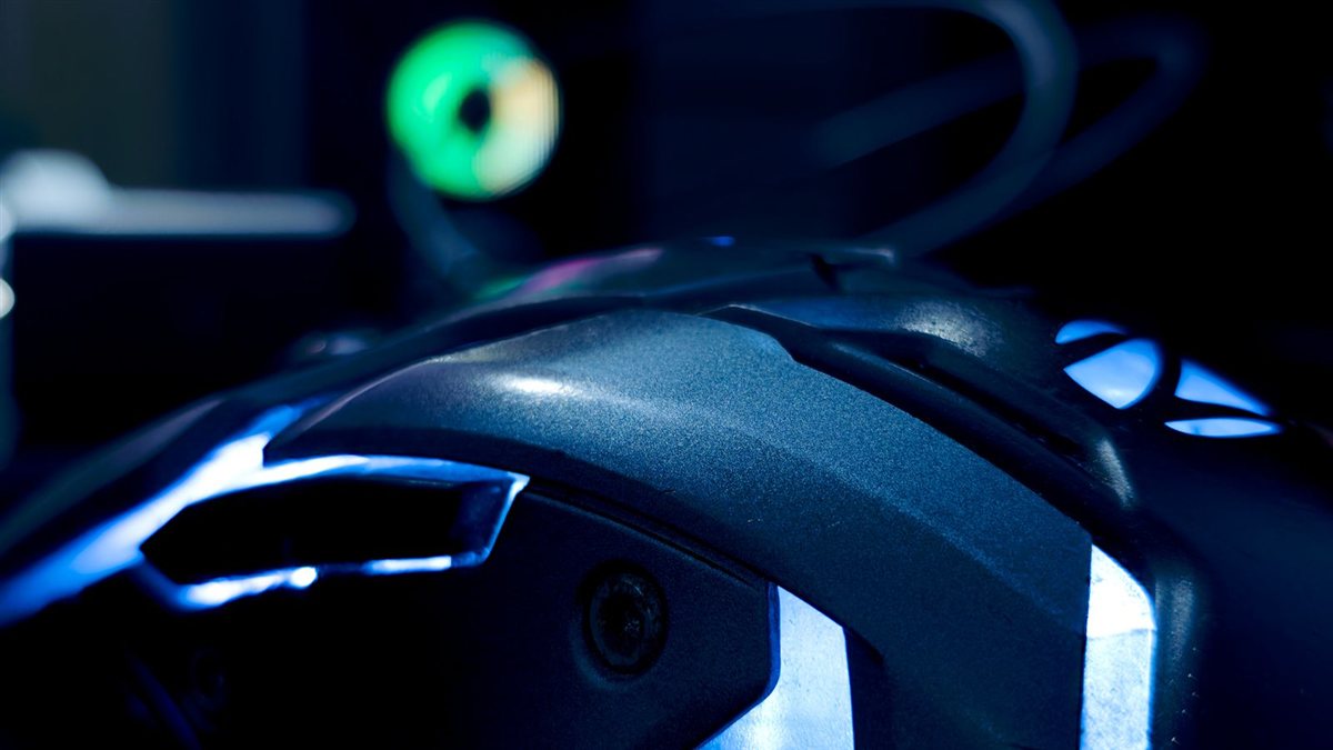 Photo d'illustration : gros plan sur une souris gaming rétroéclairée RGB posée sur un fond sombre, le périphérique qui sert à viser dans un FPS